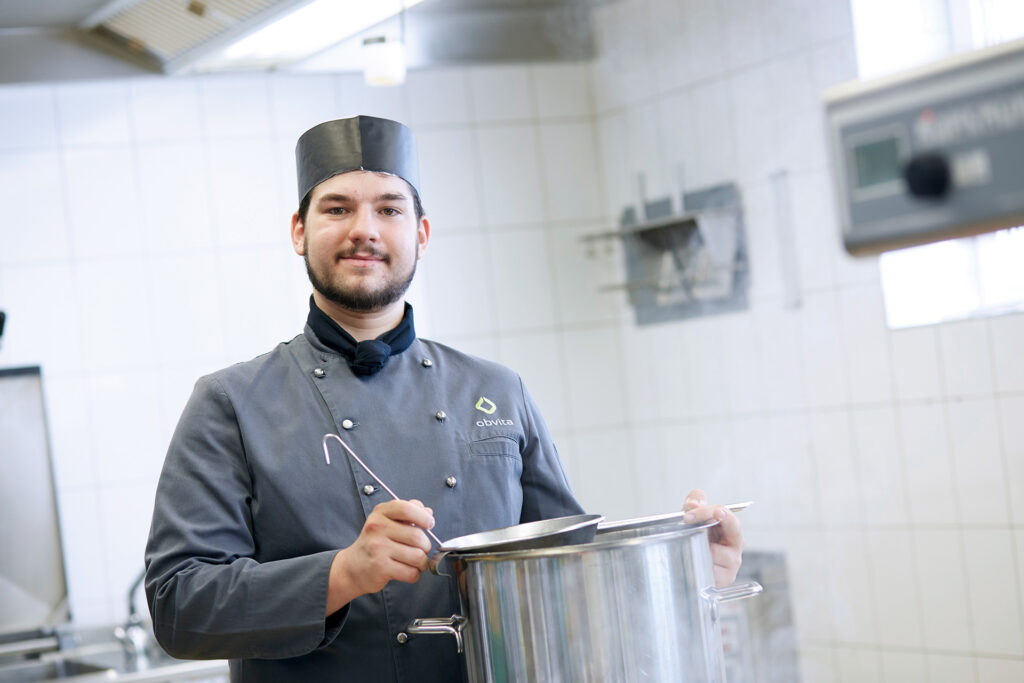 Koch beim Absieben einer Suppe